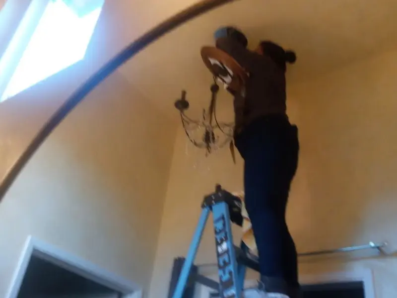 Electrician installing a chandelier in a Fuquay residence